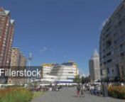 ROTTERDAM, NETHERLANDS - AUGUST 05, 2016: Panning shot of city with apartment blocks, Central Library and St. Lawrence Church. People walking in street and relaxing on green lawnnLicense this clip: https://fillerstock.com/video/8920