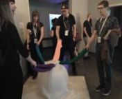 Some of the visitors playing with Olly at Ars Electronica 2019.nnOlly was on show in Postcity, Linz, as part of the Campus Exhibition: Sandbox (R)evolution, QMUL MAT.nnOlly is made by using an inflated therapy ball placed on a 3 mm felt base. The ball is wrapped in 3 mm felt sheets cut to shape by sewing together four slices of felt that adhere to the circular shape of the ball. The installation is topped with 5 stretchy lycra bands sewn on the top of the wool in which the ball it’s wrapped to